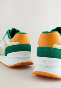 Adidași verzi și portocalii, cu un amestec de suede și materiale fine, talpă albă cu un accent portocaliu și toc texturat.