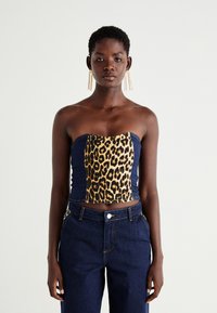 Bezdidelis viršus su leopardinėmis raštais priekyje ir tamsiai mėlyna džinsine nugarėlė, pasižymintis prigludusia forma ir siuvinėjimo detalėmis. Užsivilkta su tamsiai mėlynais džinsais.