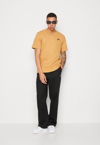 Nike Sportswear CLUB TEE - T-shirt básica - gold