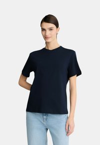 T-shirt a maniche corte blu navy in cotone, con scollo rotondo e vestibilità comoda, abbinato a jeans in denim chiaro.