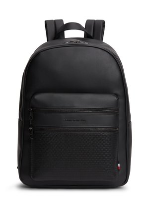 Sac à dos en cuir noir avec deux poches zippées à l'avant, bretelles rembourrées et une petite étiquette drapeau rouge, blanc et bleu sur le côté.
