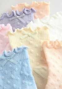 Zestaw dzierganych skarpetek w pastelowych kolorach: niebieskim, różowym, lawendowym, żółtym, białym i brzoskwiniowym. Charakteryzują się falbaniastymi brzegami i małymi kokardkami. Teksturowany wzór w kropki.