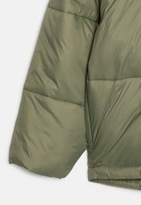 Olivgrön puffjacka med en kviltad design, med en slät ytstruktur och en något överdimensionerad passform i ärmarna.