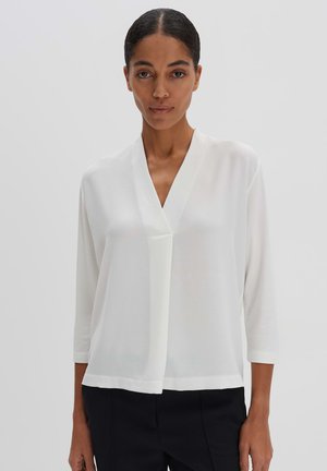 White blouse with three-quarter sleeves, v-neck design, lightweight fabric, and a loose fit. Features a subtle, smooth texture.