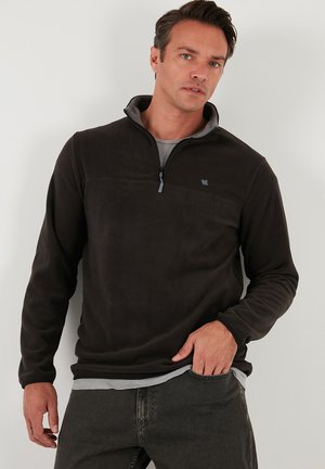 Dark grey fleece pullover with a half-zip neck, tonal shoulder panel, and subtle logo. Soft texture and relaxed fit. Suitable for casual wear.