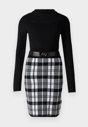 Bluza neagră cu mâneci lungi, cu un design mulat, asortată cu o fustă creion alb-negru în carouri, prevăzută cu o curea cu accesoriu circular.