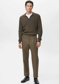 Brown ribbed knit sweater with a V-neck, paired with tailored brown trousers and black leather ankle boots. Classic fit and clean lines.