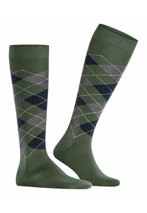 Chaussettes montantes couleur vert foncé avec un motif argyle en losanges gris et bleu marine, ornées de coutures blanches le long des bords des losanges.