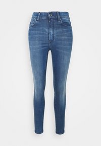 Jeans ajustados en denim azul medio con un acabado desgastado. Cuenta con cinco bolsillos, una cremallera y presillas para cinturón. Textura suave con un ligero estiramiento.