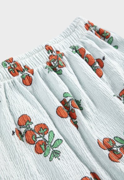 Tissu bleu clair texturé avec une ceinture élastique présentant un motif de tomates orange avec des feuilles vertes.