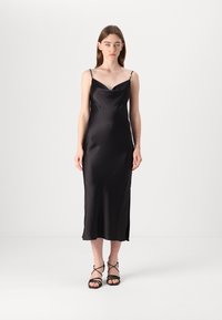 Black satin slip dress with a cowl neckline, thin straps, and a side slit. The fabric has a smooth, shiny texture.