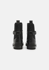Botas de tobillo negras con un respaldo de cuero texturizado de estampado de serpiente, paneles laterales elásticos y una suela de goma duradera. Presentan un acento de correa.
