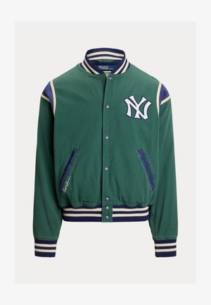 Zöld varsity dzseki fehér New York logóval, ellentétes sötétkék részletekkel, bordás mandzsettákkal és gallérral. Patentos gombokkal és oldalzsebekkel rendelkezik.