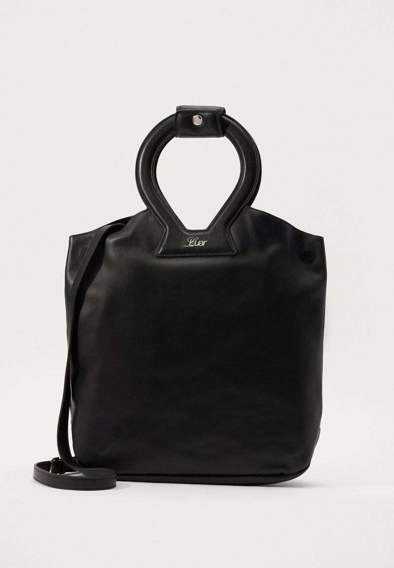 Μαύρη δερμάτινη τσάντα tote με μοναδική στρογγυλή λαβή, ομαλή υφή, ρυθμιζόμενη ιμάντα ώμου και διακριτική αναγραφή του brand.