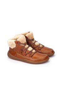 Botas de tobillo de cuero marrón con cuello de piel sintética beige, cordones en contraste y detalles de costura. Textura suave y diseño de punta redondeada.