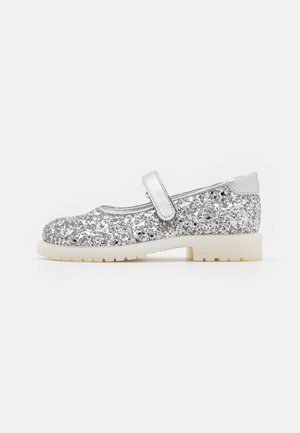 Chaussure Mary Jane pailletée argentée avec une bride unique et une semelle blanche conçue pour enfants, montrée de profil sur fond blanc.