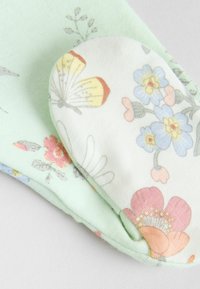 Tissu à motif floral dans des couleurs pastel, comportant des papillons et des fleurs. Deux couches : une base vert clair et un dessus blanc avec de multiples motifs floraux.