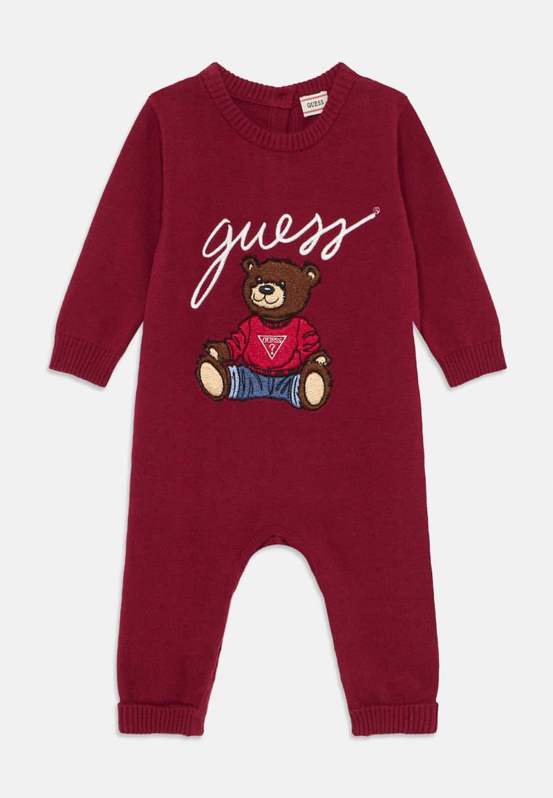Tutina in maglina color bordeaux con maniche lunghe, caratterizzata da un orsetto ricamato che indossa una camicia rossa e jeans blu, con la scritta "guess" in bianco.