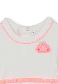 Hvit bomullsbluse med bølget neonlyserosa kant, med en glad sky-applikasjon med en sølvsløyfe og rosa kinn.