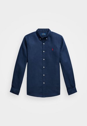 Navy sininen pellavapaita, jossa on napitettava kaulus, pitkät hihat ja pieni punainen polo-logo rinnassa. Sisältää valkoisia nappeja.