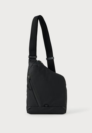 Mala preta assimétrica de ombro com alça ajustável, bolso com fecho de correr e discreto logótipo "BOSS" na frente.