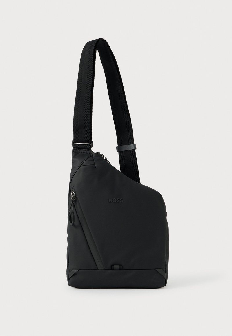 Melnā asimetriskā soma pāri plecam ar regulējamu siksnu, rāvējslēdzēja kabatu un nemanāmu "BOSS" logotipu priekšpusē.