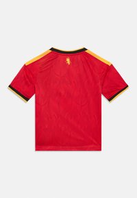 Röd sporttröja med korta ärmar, med ett subtilt flamemönster, svarta och gula detaljer och en emblemdesign på baksidan.