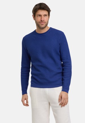 Blauw gebreide trui met een ronde halslijn en lange mouwen, gecombineerd met witte textuurbroek.