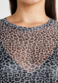 Sheer gray top featuring a leopard print pattern in brown and black, with a round neckline and subtle shimmer detail along the edges.
