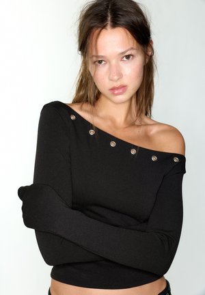 Black long-sleeve top featuring an off-shoulder design with silver hardware accenting the neckline. Soft fabric with a fitted cut.
