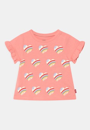 T-shirt rosa de manga curta com mangas em babados, apresentando um padrão repetido de corações arco-íris em várias cores na frente.
