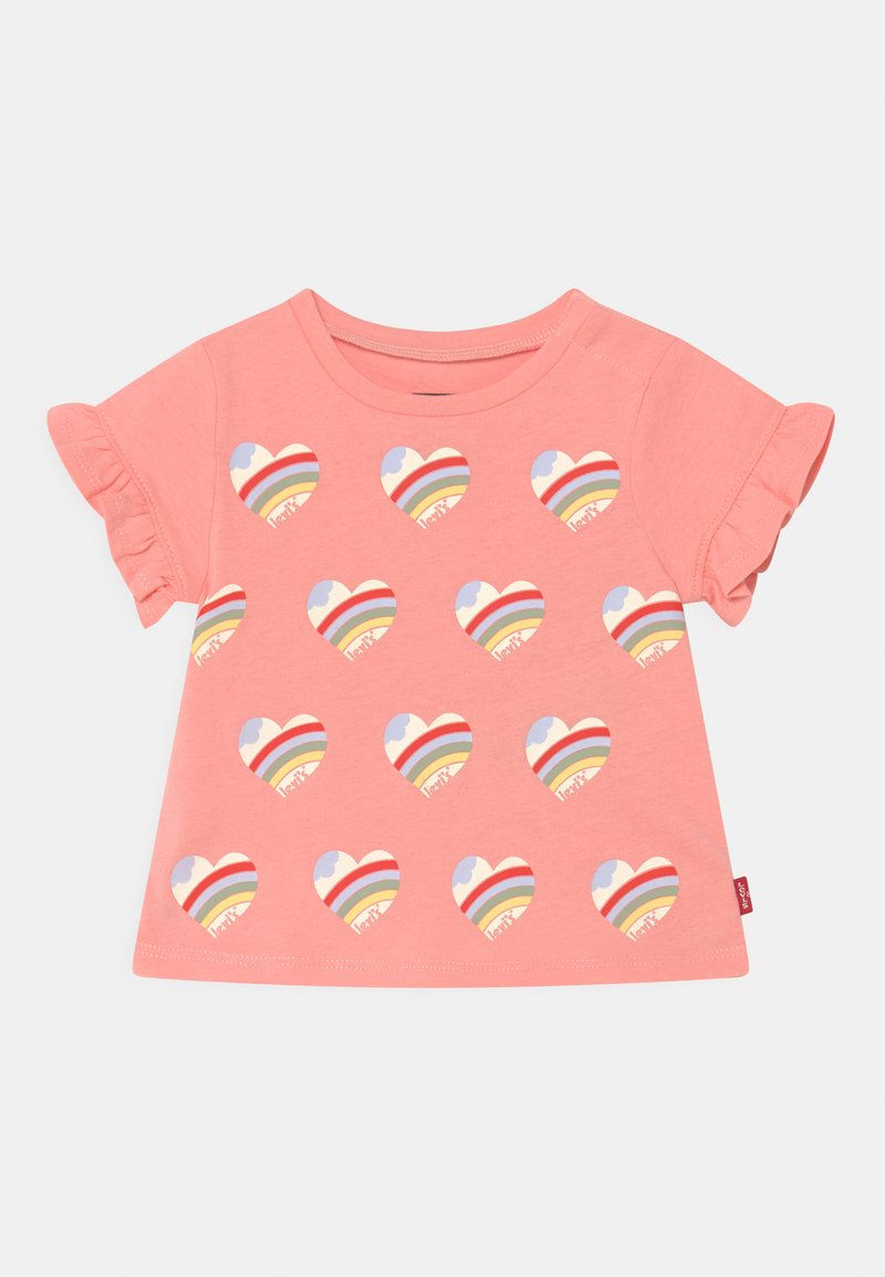 T-shirt rosa de manga curta com mangas em babados, apresentando um padrão repetido de corações arco-íris em várias cores na frente.