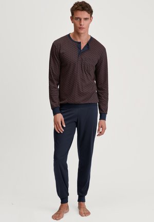 Marineblauw en bordeaux gekleed loungemode set, bestaande uit een langärmlige top met een knoopsluiting bij de hals en een broek met elastische taille en cuffs.
