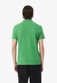 Groene polo met korte mouwen, voorzien van een klassieke kraag en een zachte textuur. Heeft een rechte snit en een minimalistisch ontwerp zonder versieringen.