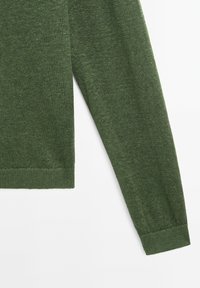 Manche longue d'un pull vert en tricot avec poignets et ourlet côtelés sur fond blanc.