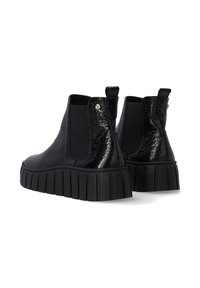 Schwarze Knöchelschuhe aus glänzendem Material mit elastischen Seitenpartien, dicken schwarzen Gummisohlen und einer strukturierten Oberfläche.