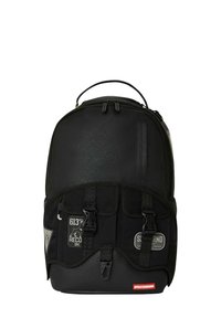 Mochila negra con tela texturizada, correas ajustables, dos hebillas en la parte frontal y parches con logotipo. Compartimento principal con cremallera y bolsillo lateral.
