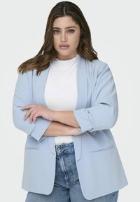 Heledsinine bleiser, mis on valmistatud siledast kangast, omades lõdva lõikega, laiade kraede ja kahe esipocket'iga, mille all on valge topp.