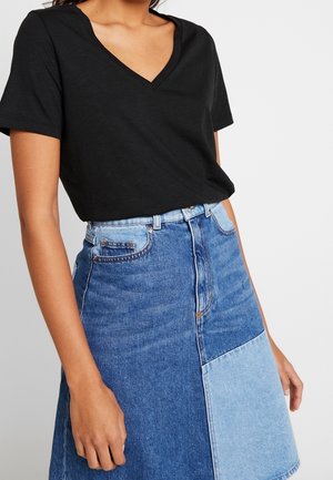 Musta lyhythihainen v-kaula-aukkoinen t-paita, joka on yhdistetty farkkuhameeseen, jossa on kirjontakuvio eri sinisen sävyissä.