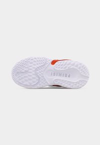 Semelle en caoutchouc blanc texturé d'une chaussure avec le nom de la marque "PRIMIGI" embossé au centre et des accents orange visibles sur le côté.