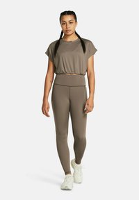 Brun kortärmad t-shirt och högmidjade leggings. Mjuk, elastisk tyg med en slät yta. Matchas med ljusa träningsskor.