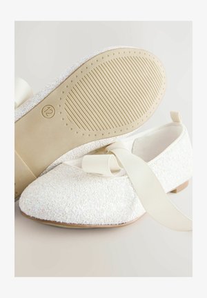 Balerini albe cu un material superior texturat și strălucitor, vârf rotund moale și talpă plată din cauciuc. Include o panglică albă pentru prindere.