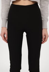 Melni legingi, izgatavoti no elastīga auduma, ar elegantu dizainu un gludu tekstūru. Iekļauj augstu jostu komfortam.