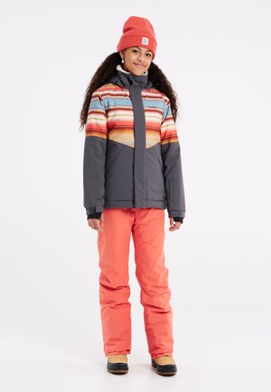 Veste de ski avec des rayures horizontales multicolores dans des tons d'orange, pantalon gris et bottes noires ; tissu chaud, fermeture éclair et capuche.