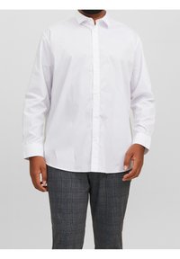 Biała koszula z długim rękawem na guziki, z klasycznym kołnierzykiem, gładkim materiałem i starannie ułożonymi guzikami. W połączeniu z teksturowanymi spodniami w kratę.