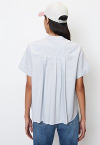 Ljusblått randigt kortärmat skjorta, plisserad baksida, mjukt tyg, kombinerat med blekta blåjeans och en vit keps med rosa skärm.