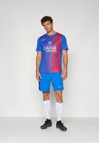 Fato de futebol em gradiente azul e vermelho, com um logótipo e a impressão "QATAR AIRWAYS", combinado com calções azuis e meias brancas. Chuteiras pretas.