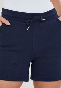 Marineblauwe katoenen shorts met een geribde tailleband, verstelbaar trekkoord en twee zijzakken. Gladde textuur en een casual ontwerp.