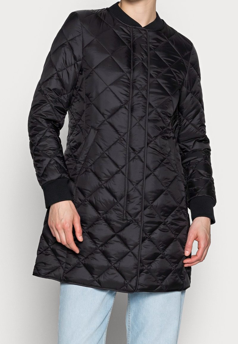 Abrigo largo negro acolchado con cuello redondeado, que presenta un cierre delantero con cremallera y puños acanalados. Tela suave y brillante con textura de patrón de diamantes.