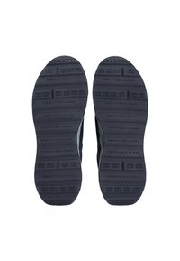 Suela de zapato con goma texturizada, que presenta patrones en relieve y un logo en relieve. Color predominantemente oscuro, diseñada para tracción y durabilidad.